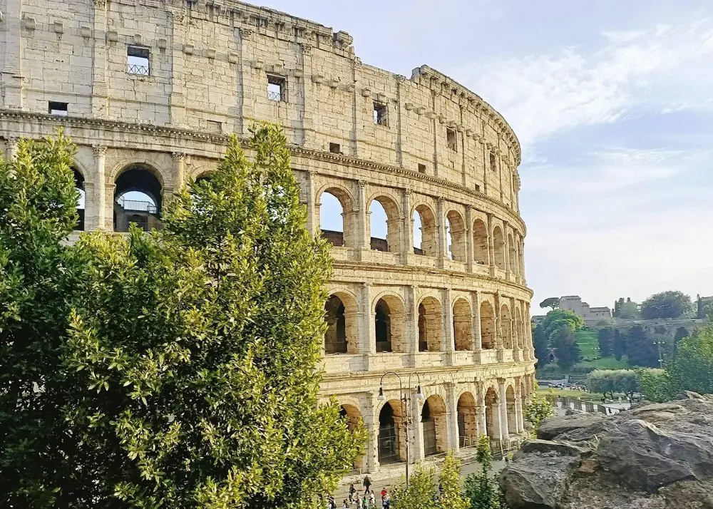 The Colosseum exterior with visitors walking along the barrier in front
