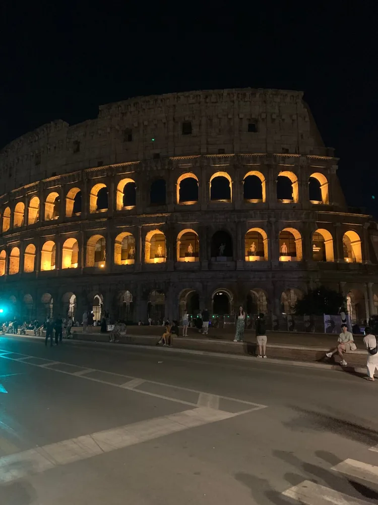 The Colosseum lit at night with its arches glowing gold